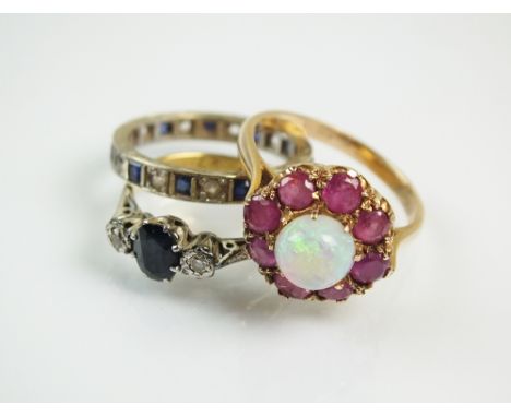 An opal and ruby cluster ring, designed as a central round cabochon opal within a border of eight round mixed cut rubies, tog