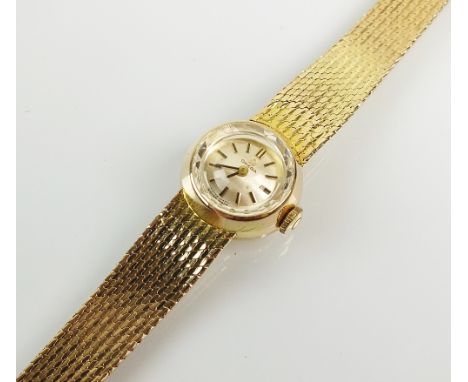 A Lady's 9ct gold Omega bracelet watch, the circular silvered dial with batons, manual wind, the 9ct gold textured tapered br