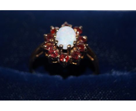 9 ct Gold dress ring set with central opal surrounded by garnets Size K