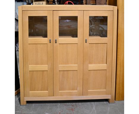 A light oak cabinet, late 20th c,&nbsp;three part-glazed doors enclosing shelves, 129cm h; 125 x 38cm  Some light bumps to th