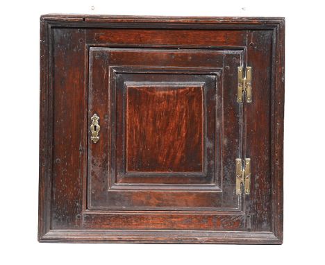 A George III oak mural cupboard, the interior with shelf enclosed by a moulded square shaped door with raised and fielded pan