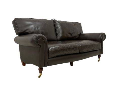 Traditional shape two seat sofa upholstered in brown leather, rolled arms, on turned feet with brass cups and castorsDimensio