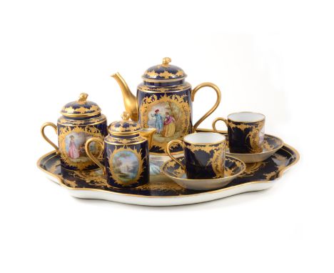 A Sevres style cabaret set, probably Limoges, late 19th century, Bleu de Roi ground with well painted panels in the manner of