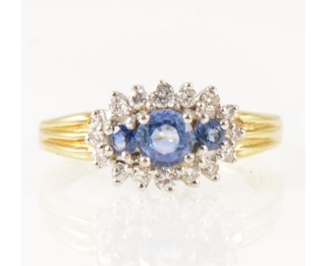 A sapphire and diamond boat shape cluster ring, three sapphires surrounded by sixteen brilliant cut diamonds graduating in si