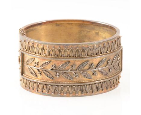 A mid 19 th Century yellow metal 33mm wide half hinged bangle, applied with beaded rope work leaves and berries, internal dim