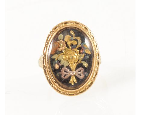 A 19 th Century three colour gold ring, the oval table with a multi colour gold ribbon tied bouquet with fine engraved surrou