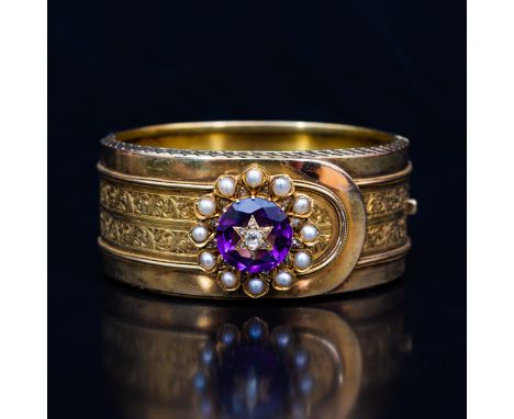 A late 19 th Century yellow metal bangle with an amethyst, diamond and pearl cluster. the 25m wide half hinged bangle having 