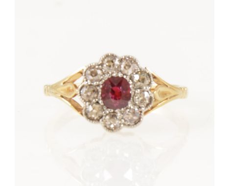 A ruby and diamond cluster ring, the oval ruby claw set and surrounded by nine milgrain set old cut diamonds in a yellow and 