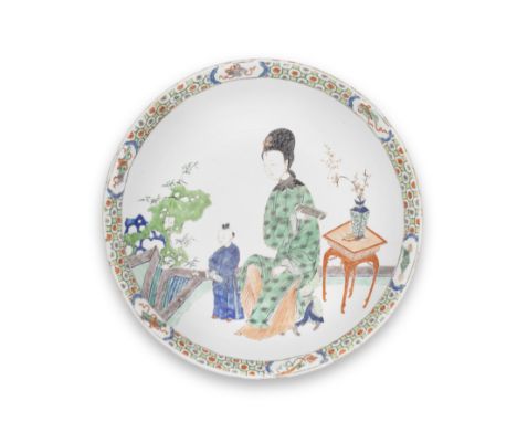 A famille verte 'Lady and boy' saucer-dishKangxiFinely enamelled to the interior with an elegant lady holding a book in her r