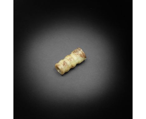 A yellow and russet jade tubular beadEastern Zhou DynastyThe expertly-hollowed cylinder carved around the exterior with five 