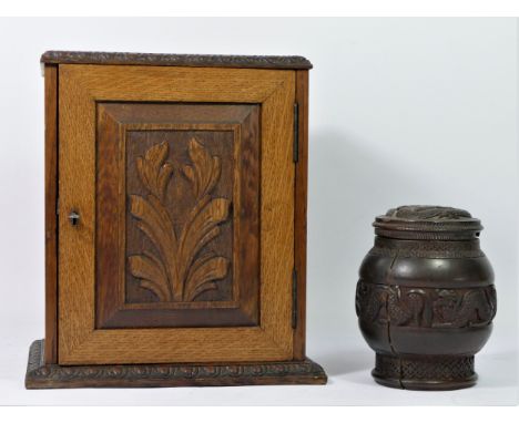 A late Victorian smokers cabinet, having carved panel door enclosing a fitted interior, incorporating single drawer, on a car