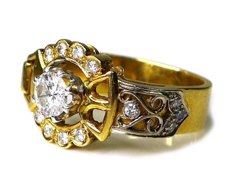 An 18ct gold and diamond ring of ornate buckle design, the central brilliant cut diamond of approximately 0.35ct, 4.5 by 2.5m