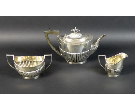 A George V three piece silver tea service, of boat form with part reeded lower bodies, each engraved with a single 'G', compr