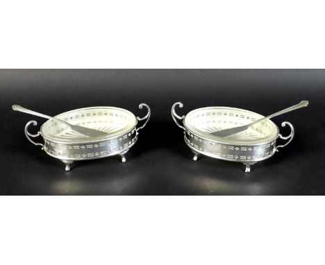 A pair of Elizabeth II silver butter dishes with matching butter knives, of oval form with with twin scroll handles and pierc