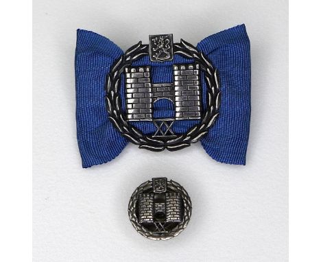 A Finnish silver heraldic pin, the symbol relating to the ancient city of Turku, set on a blue taffeta ribbon, Helsinki 1971,