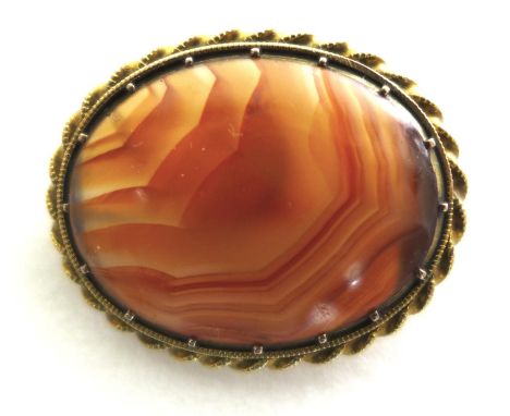 A 19th century fire banded agate brooch, of polished oval form, in an unmarked 14ct yellow gold milgrain twist border, pin fa