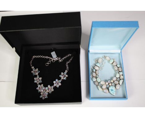 Two boxed statement articulated silver and gemstone necklaces. One of a floral design set with blue topaz, amethyst and rainb