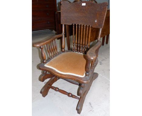 An early 20th century Shaker style oak stick back rocking armchair