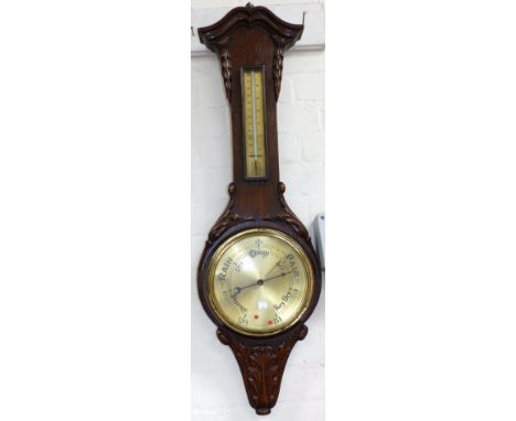 An Edwardian carved oak barometer with thermometer