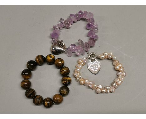 An amethyst bracelet, freshwater pearl bracelet and a tigers eye bracelet.