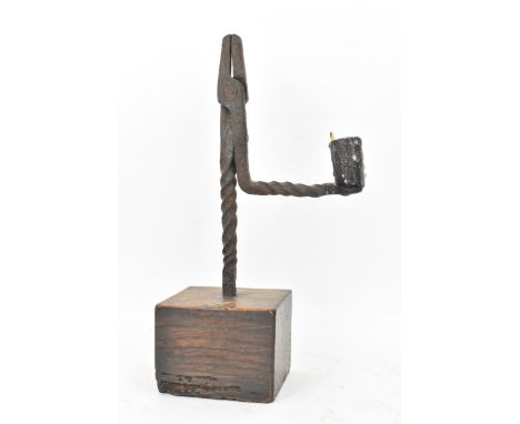 An 18th century wrought iron rush-light holder, with a candle socket arm raised on an oak base, 25cm high 