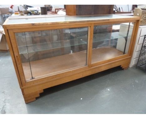 An Art Deco haberdashers glazed display cabinet with sliding doors, single shelf and brass rule, 81 x 57.5 x 178cmL