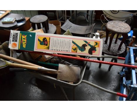 A metal wheelbarrow with garden tools and two paraffin lamps