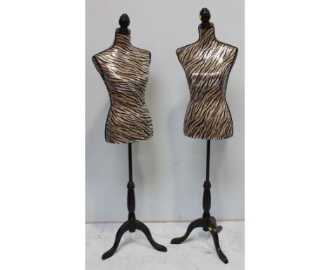 A pair of modern dress-maker's mannequin torsos, with zebra-striped sequined covers, raised on adjustable painted wooden trip