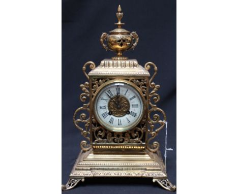 A French mantel clock with eight-day movement striking on a bell, in ornate pierced brass case with enamel dial, Roman numera