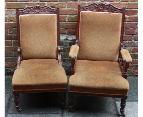 An Edwardian armchair and matching nursing chair with carved walnut frames, upholstered in gold velvet on ceramic castors.