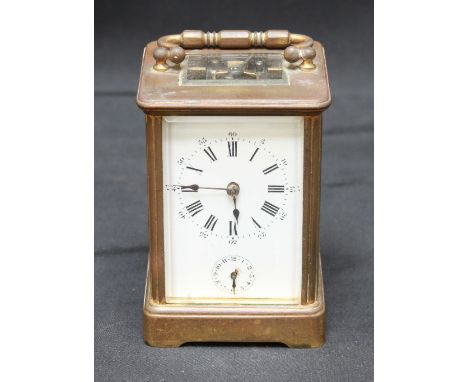 A brass cased carriage clock with white enamel dial and black Roman numerals, with subsidiary alarm dial and striking on a si