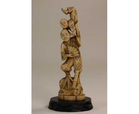 Carved ivory Okimono sculpture of a man balancing on a rock with  a fan in his hand and a young acrobaat on his shoulder, Jap