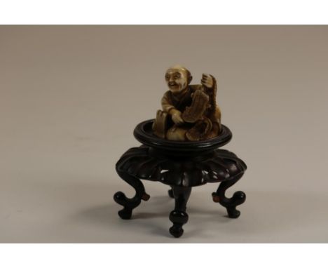 Carved ivory Netsuke of a man repairing sandals, Japan ca. 1900,  h. 3,5 cm.  The item comes with a certificate of authentici