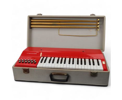 A mid 20th century Italian Companion electric keyboard, red plastic in original fixed carry case and screw on tripod legs, ca