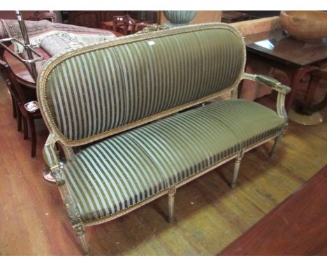 A CONTINENTAL CREAM PAINTED AND PARCEL GILT SETTEE with flowerhead cresting above a ribbon frame with upholstered back and se