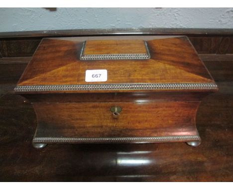 A GOOD REGENCY MAHOGANY TEA CADDY of sarcophagus outline the rectangular hinged lid with gadrooned rim and concave frieze on 