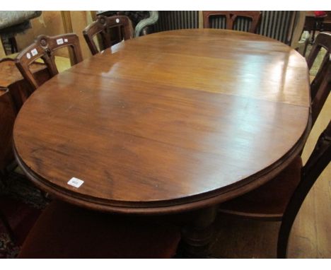 AN EDWARDIAN MAHOGANY TELESCOPIC DINING TABLE of oval outline with one loose leaf raised on ring turned legs with brass and p