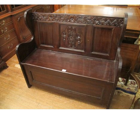 A TEAK HALL BENCH with panelled and carved back the seat with lift top 105cm wide