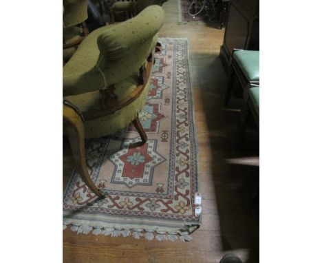 A WOOL RUG the light pink and rust ground with central rectangular panels with stylized foliage within a conforming border 24