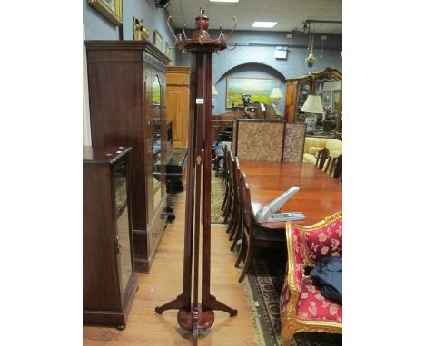 A MAHOGANY HAT AND COAT STAND the circular revolving top with brass hooks and urn finials raised on reeded supports on platfo