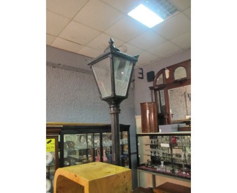 A SET OF THREE CAST IRON LAMP POSTS with tapering glazed hoods 265cm high