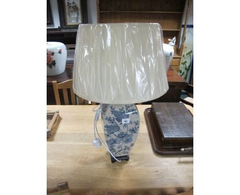 A PORCELAIN TABLE LAMP the white and blue ground decorated with flowerheads and foliage raised on a hardwood base with pleate