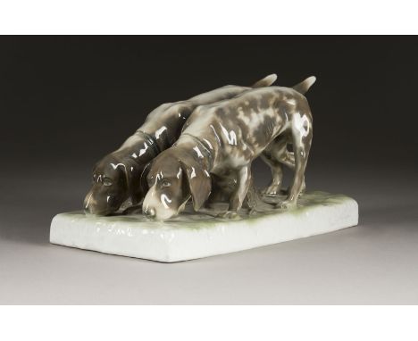 KURT SEHRERTätig im 20. Jh.PAAR JAGDHUNDE Deutsch, Fraureuth, um 1920 Porzellan, polychrom staffiert. H. 14 cm, L. 29 cm. Grü