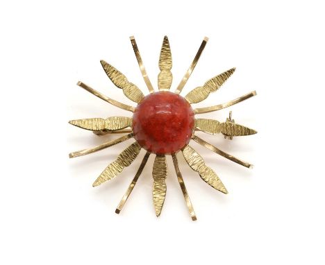 A floral brooch, modelled as a stylised flowerhead, with a red hardstone cabochon within textured and polished gold petals, t