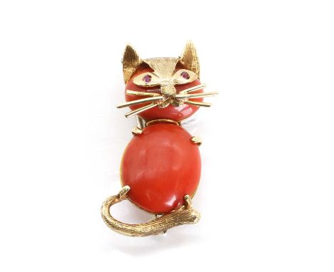An 18ct gold coral and ruby novelty brooch, c1960s, in the form of a cat, with an oval coral cabochon body and head, to a pie