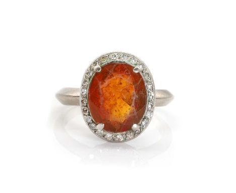 An orange citrine and diamond cluster ring,  the oval mixed cut citrine claw set to a surround of single cut diamonds, to a w