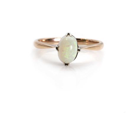 An Edwardian opal ring,  with an oval opal cabochon, 7 x 5mm, set to a yellow collet with white doubled claws, into tapered s