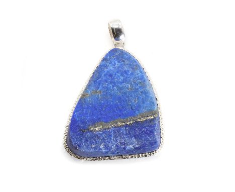 A lapis lazuli pendant a free form rough lapis lazuli tablet, 45mm x 38mm, bezel set to a silver mount, with an articulated o
