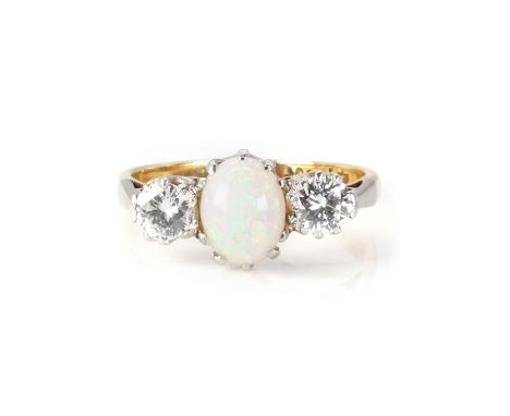 An opal and diamond three stone ring,  with a central oval opal cabochon, flanked by a round brilliant cut diamond to either 