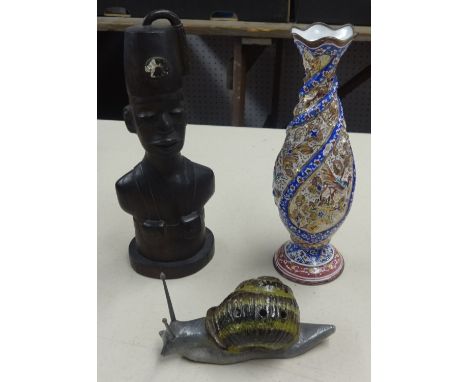 An ornate enamel decorative vase, a carved wood figure of an African and a stoneware snail model.